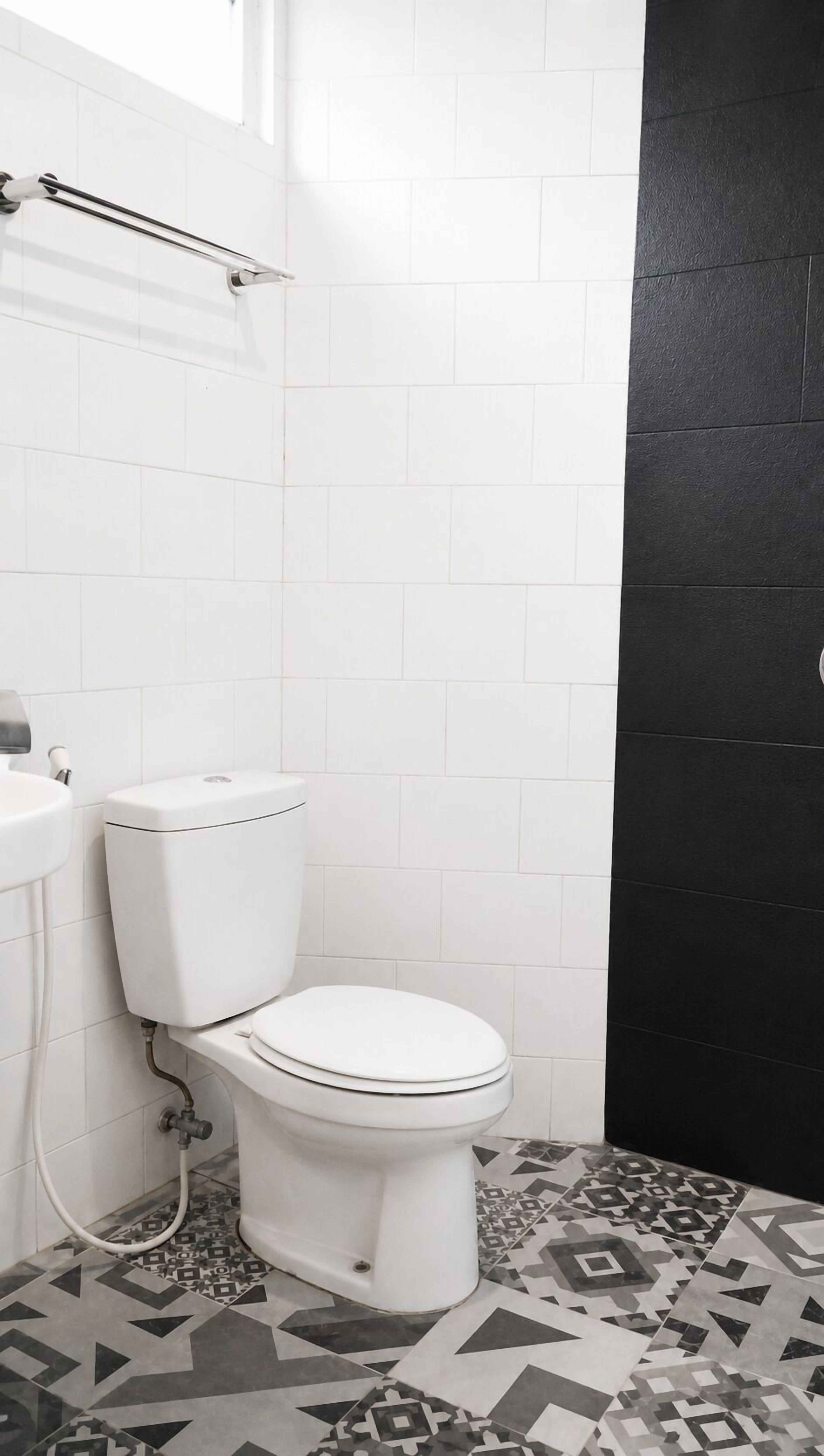 A bathroom with a toilet, sink, and patterned floor tiles.