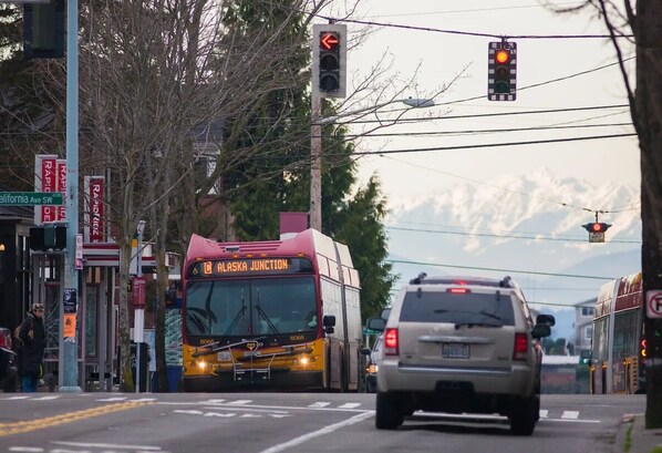 A bus labeled "Alaska Junction" approaching a traffic light at an intersection.