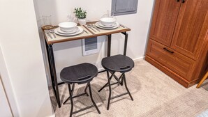 A compact kitchenette with a small table set for two, a stool, a potted plant, and a cabinet. - West Seattle Junction • Private Parking • Walkable • 15 mins from Downtown (Seattle)