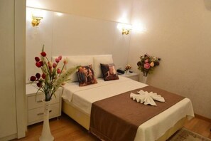Un dormitorio ordenado con cama, mesitas de noche y un jarrón de flores.