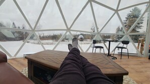 A room with a large glass dome window, a wooden table, and a brown leather chair. - Escape to Nature, Sleep Under The Stars (Zephyr)