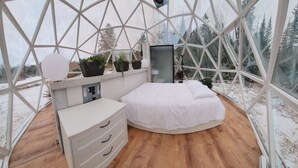A cozy, circular room with a bed, a dresser, and a small seating area. - Escape to Nature, Sleep Under The Stars (Zephyr)