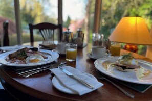 A breakfast setting with plates of food, a lamp, and a view of greenery. - Burn How Garden Hotel - Bowness on Windermere (Bowness-on-Windermere)