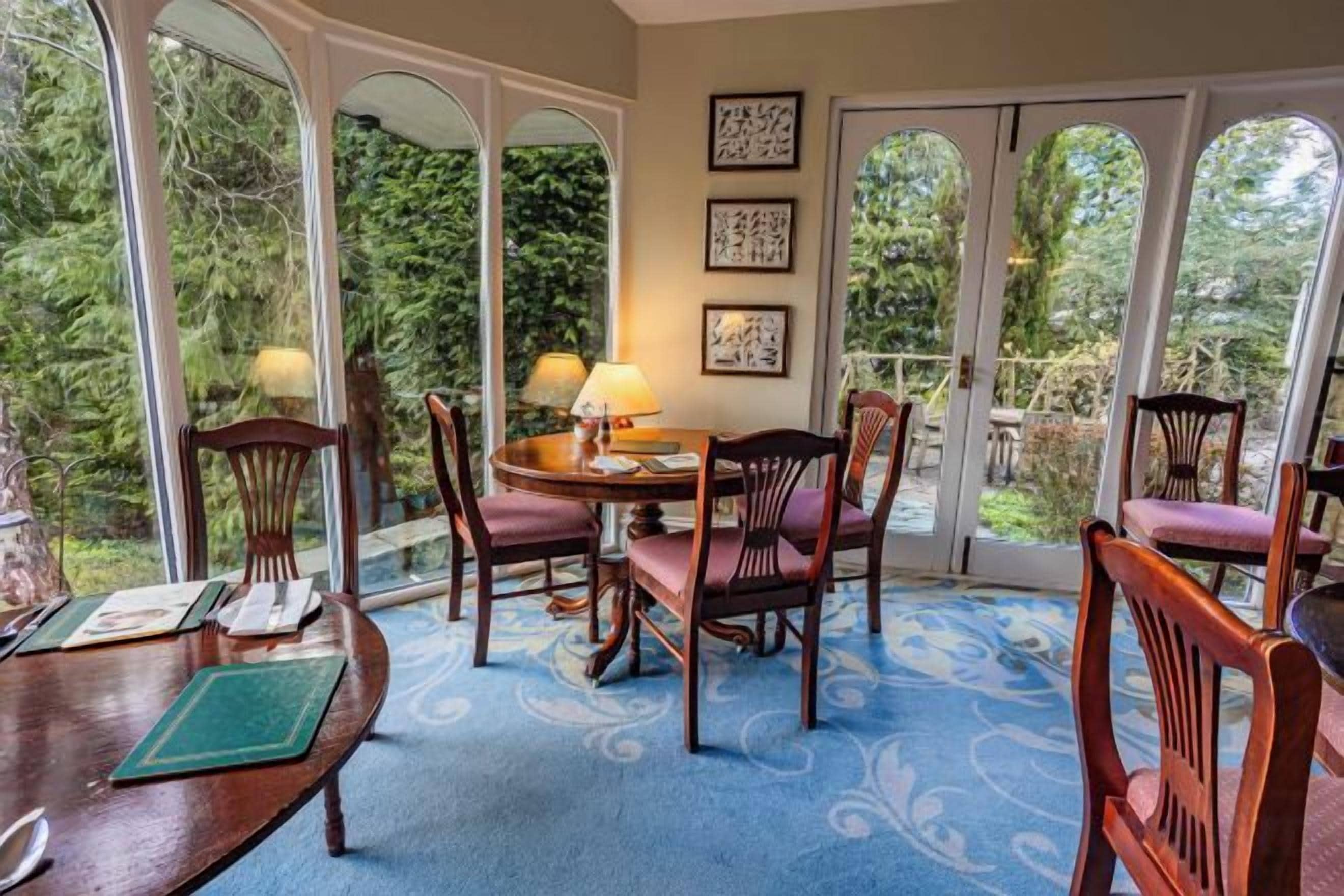 A dining area with a round table, chairs, and a view through glass doors.