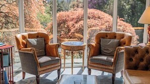 Ένα δωμάτιο με δύο δερμάτινες πολυθρόνες, ένα τραπεζάκι σαλονιού από γυαλί και ένα μικρό στρογγυλό τραπέζι.