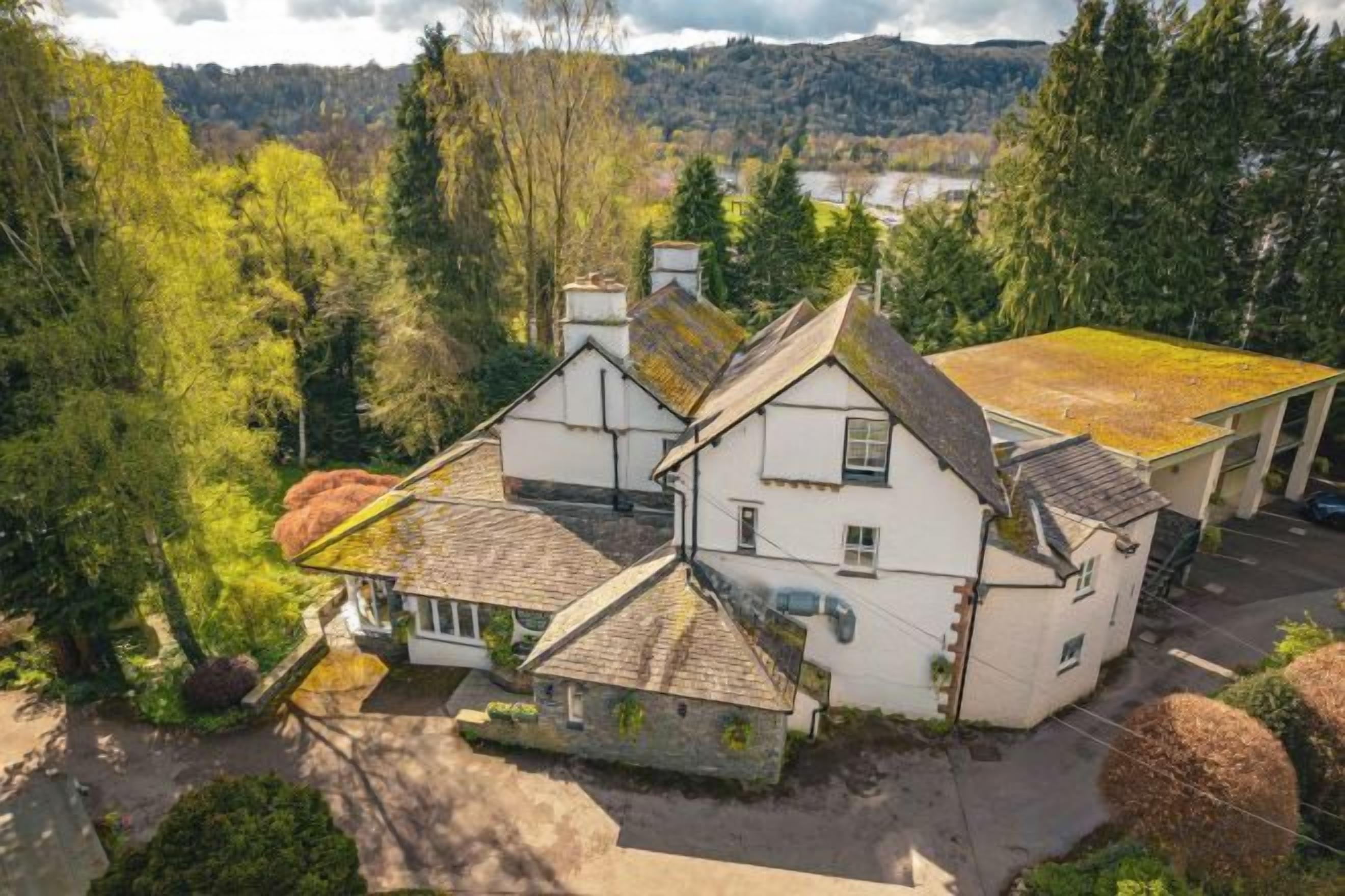 A two-story house with a traditional design, a visible chimney, and a surrounding garden.