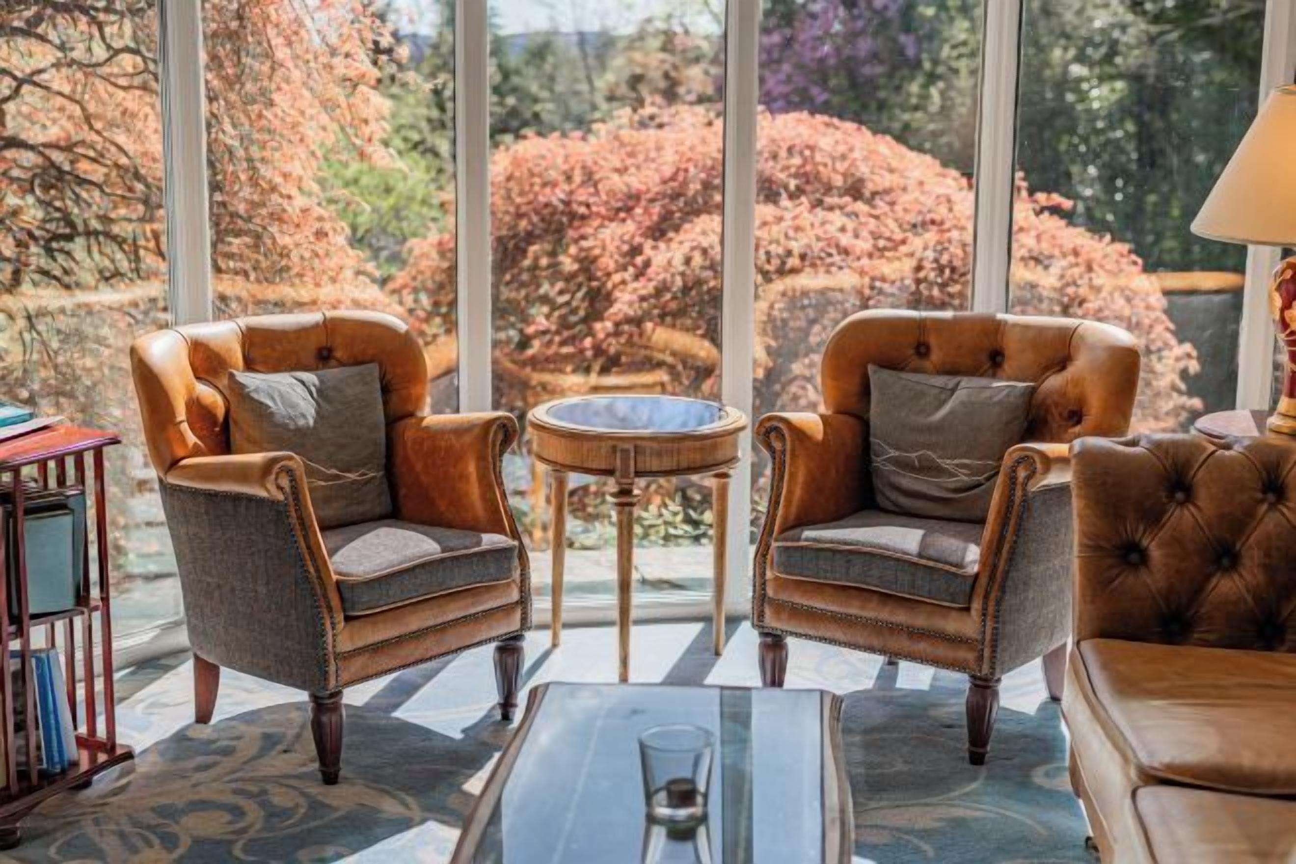 A room with two leather armchairs, a small round table, and a glass coffee table.