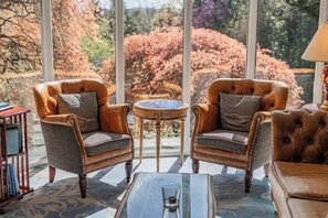 Une pièce comprenant deux fauteuils en cuir, une petite table ronde et une table basse en verre.