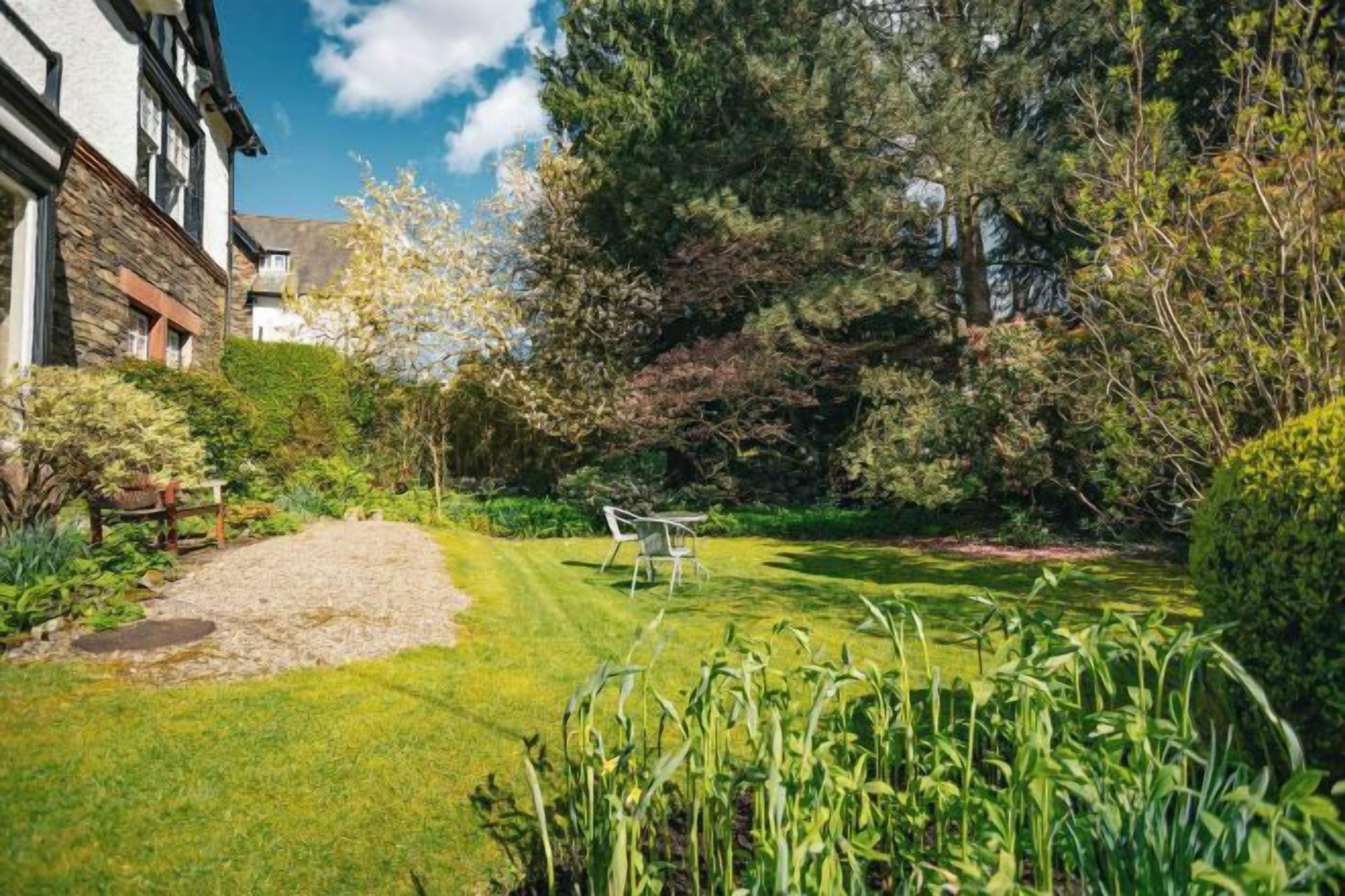 A well-maintained garden with a lawn, a wooden bench, and a table.