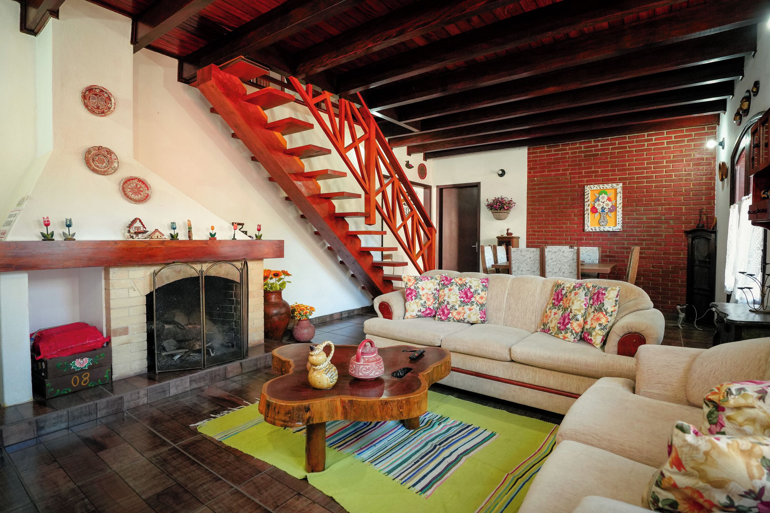 Una sala de estar con chimenea, un sofá, una mesa de centro y una escalera roja.