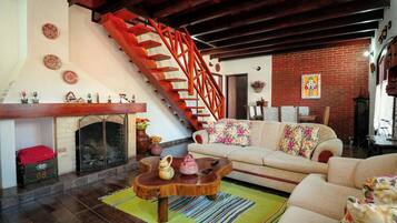 Una sala de estar con chimenea, un sofá, una mesa de centro y una escalera roja.