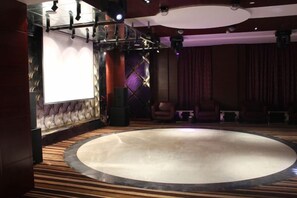 A theater with a circular stage, rows of seating, and a large screen. - Xuehu Garden Hotel (Jinan)