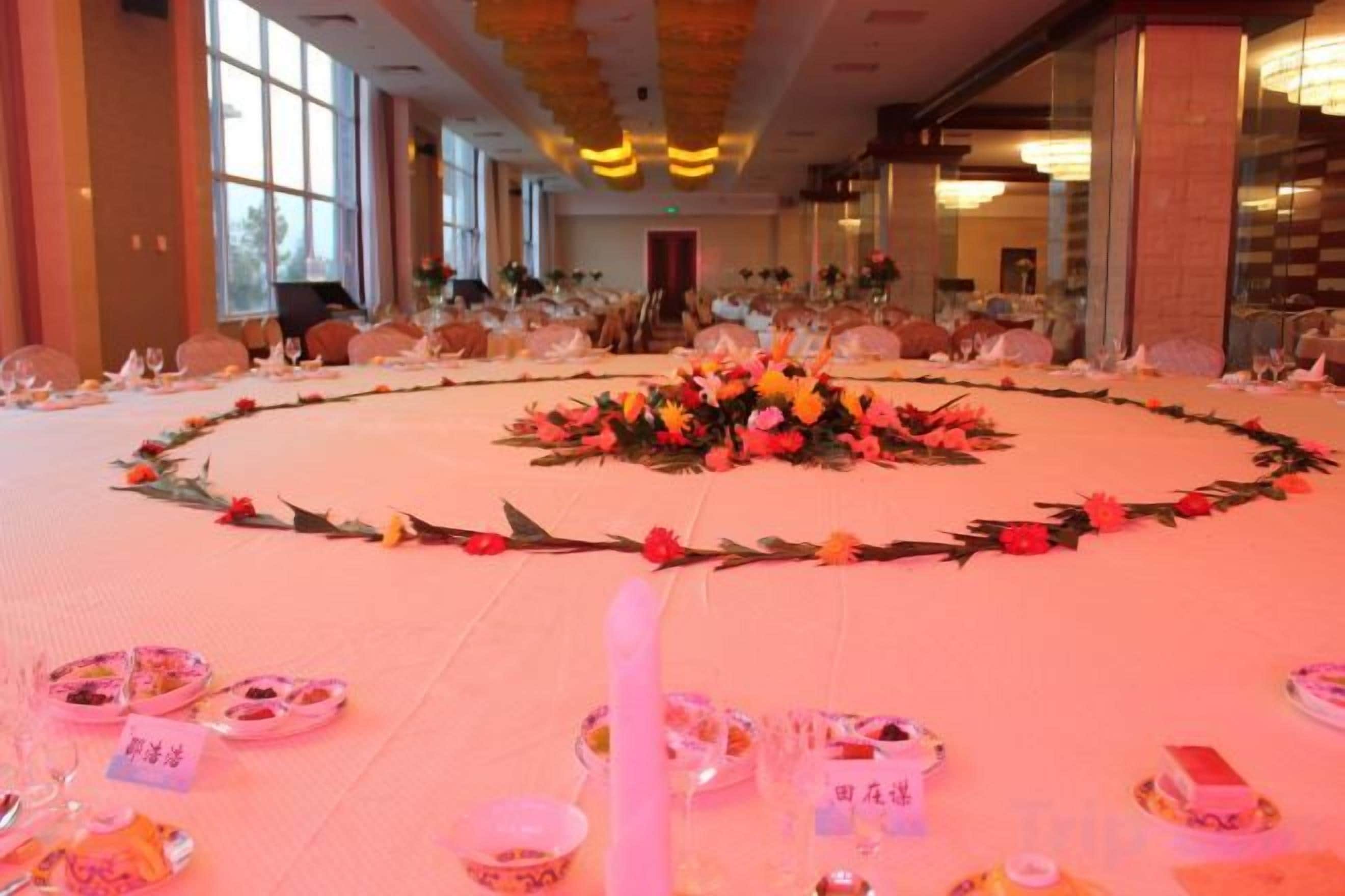 A banquet hall with round tables set for a formal event, featuring floral centerpieces and table settings.