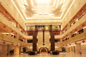 Un hall d’hôtel à plusieurs niveaux, doté d’un espace de réception central, de nombreux étages et d’un design moderne.