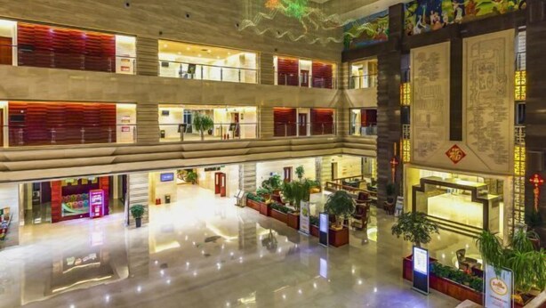 Een hotelentree op meerdere niveaus met een open centrale ruimte, diverse verdiepingen en klassieke kunstwerken.