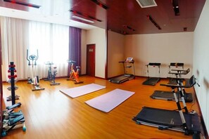 A gym with exercise equipment, mats, and a treadmill.