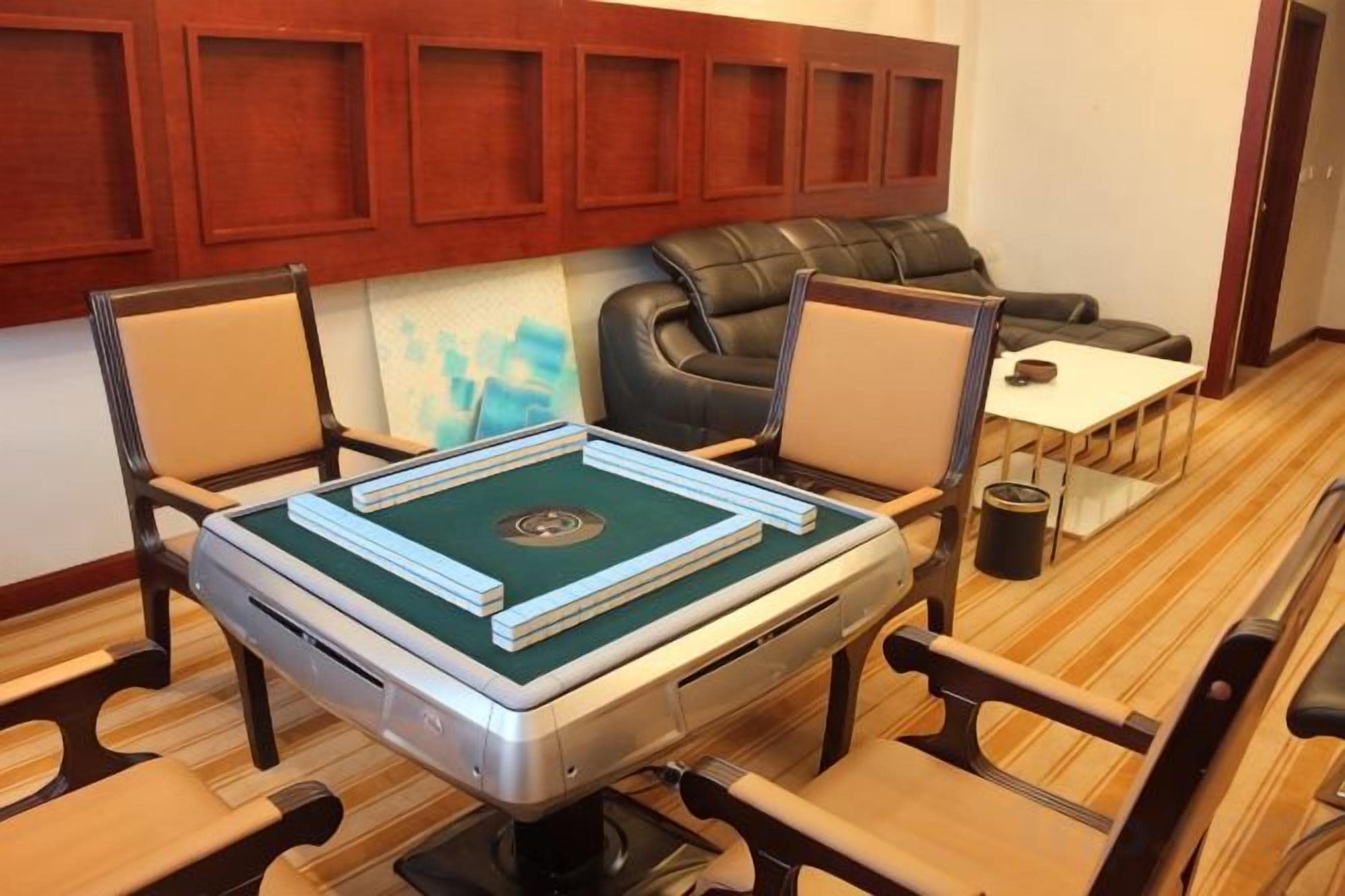 A room with a table set for a game, a sofa, and a small table with a lamp.