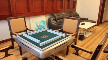 A room with a table set for a game, a sofa, and a small table with a lamp.