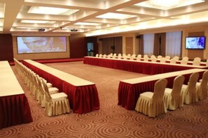 A conference room with a long table, rows of chairs, a carpeted floor, and a screen displaying a presentation. - Xuehu Garden Hotel (Jinan)