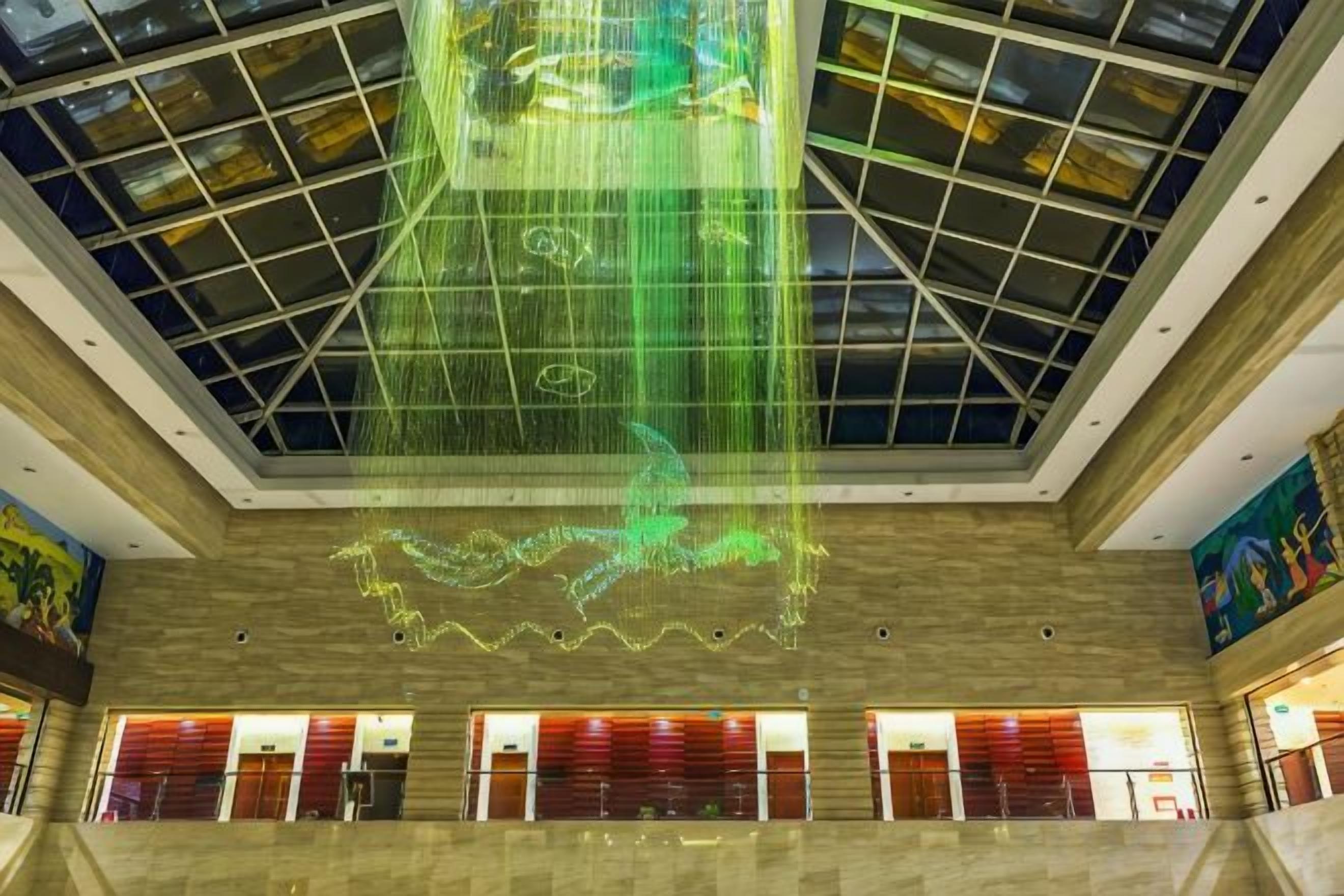 A spacious atrium with a high ceiling, a central light installation, and a view of the lower level.