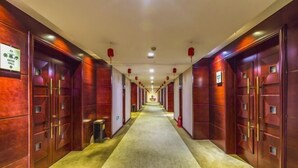 Een hotelgang met houten deuren en een vloerkleed.