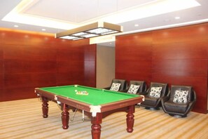 Una mesa de billar en una habitación con paredes de madera y suelo alfombrado.