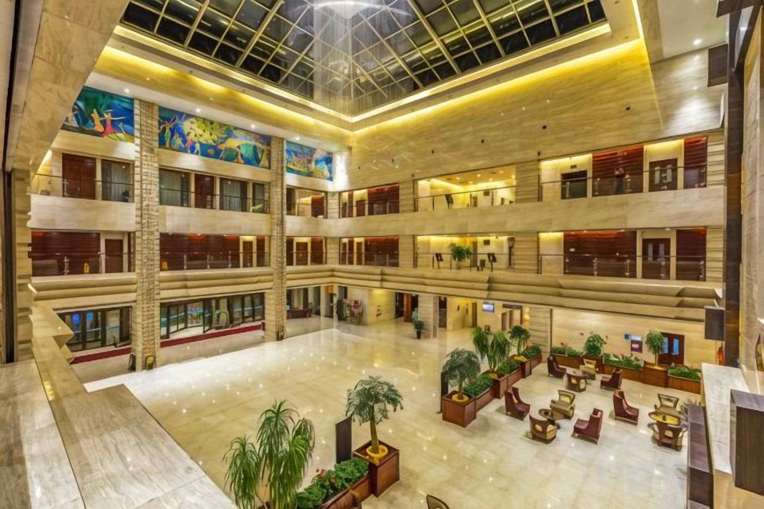 Un atrium de diversos nivells amb un sostre alt, diversos pisos i un espai central obert amb seients i plantes.