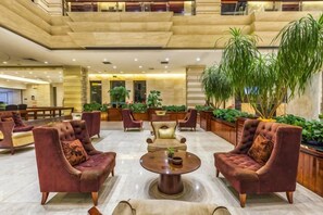 A spacious lobby with multiple seating areas, including sofas and armchairs, arranged around a central coffee table. - Xuehu Garden Hotel (Jinan)