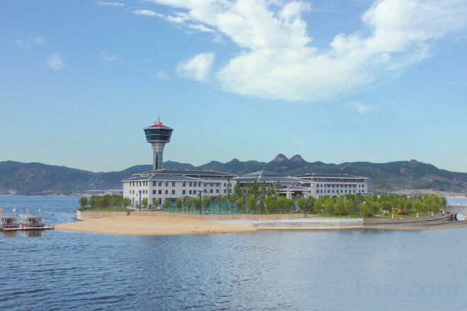 Een hotel met een toren, gelegen op een eiland met bergen op de achtergrond.