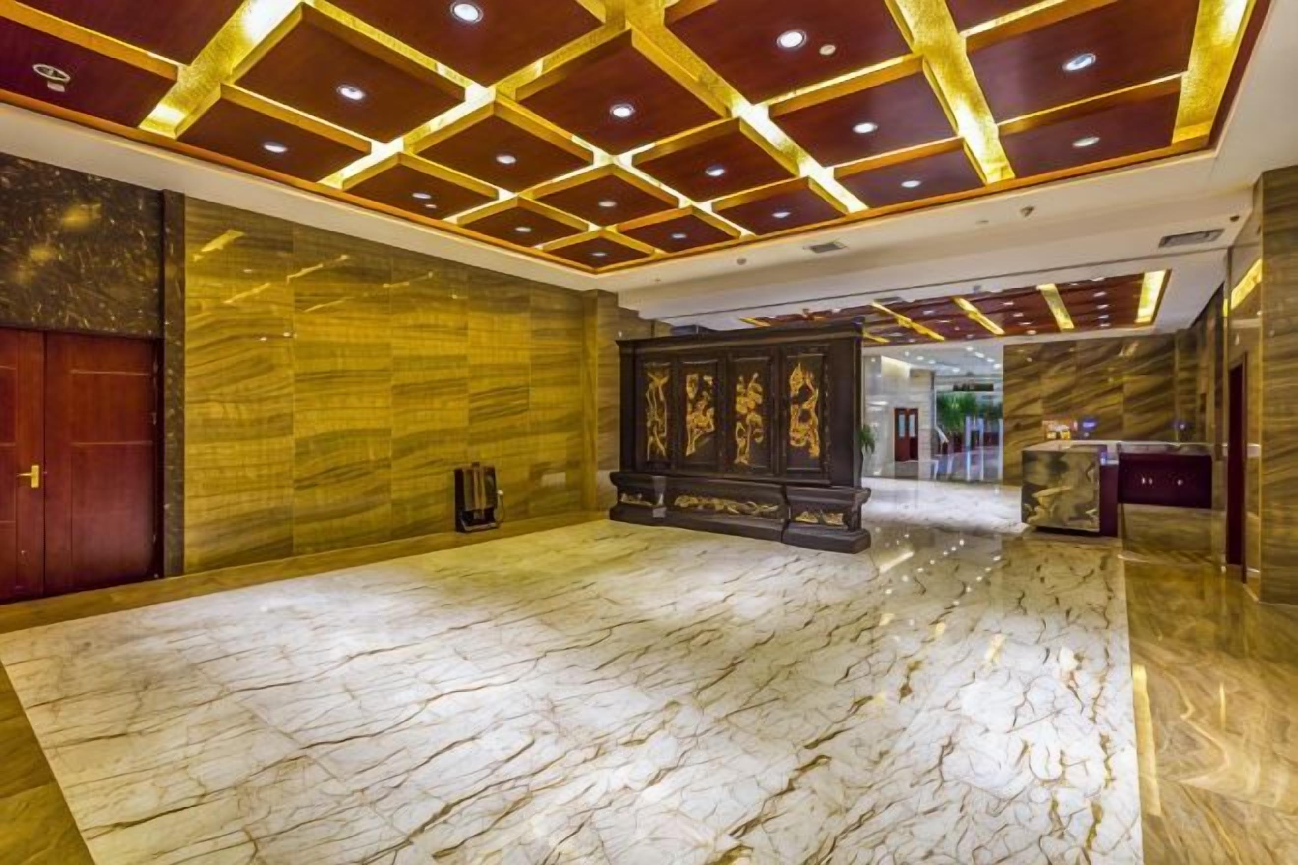 A hotel lobby with a marble floor, a reception desk, and a decorative wall.