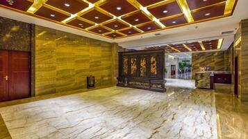 A hotel lobby with a marble floor, a reception desk, and a decorative wall.
