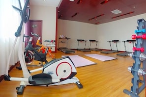 Ein Fitnessstudio mit Trainingsgeräten, Laufbändern und einem Krafttrainingsbereich.