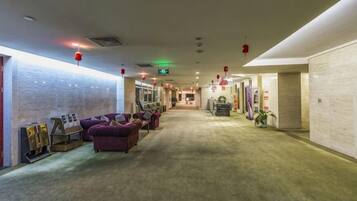 A hotel lobby with a carpeted floor, seating area with couches, and a reception desk.