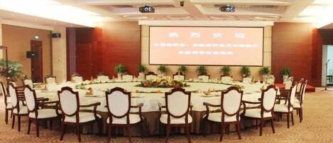 A conference room with a large screen, round tables, and chairs arranged for a meeting.