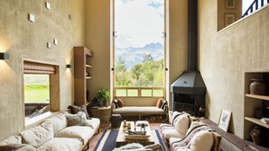 Ein gemütliches Wohnzimmer mit großem Fenster, Kamin und Bergblick.