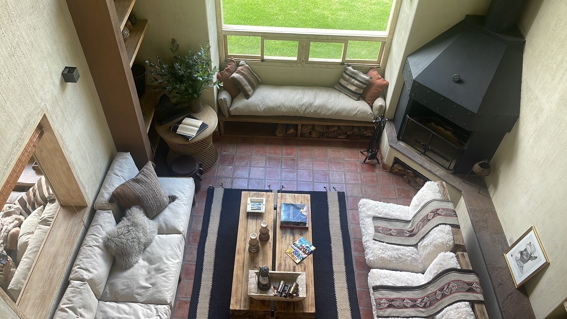 A cozy living room with a fireplace, a sofa, a coffee table, and a view of the garden.