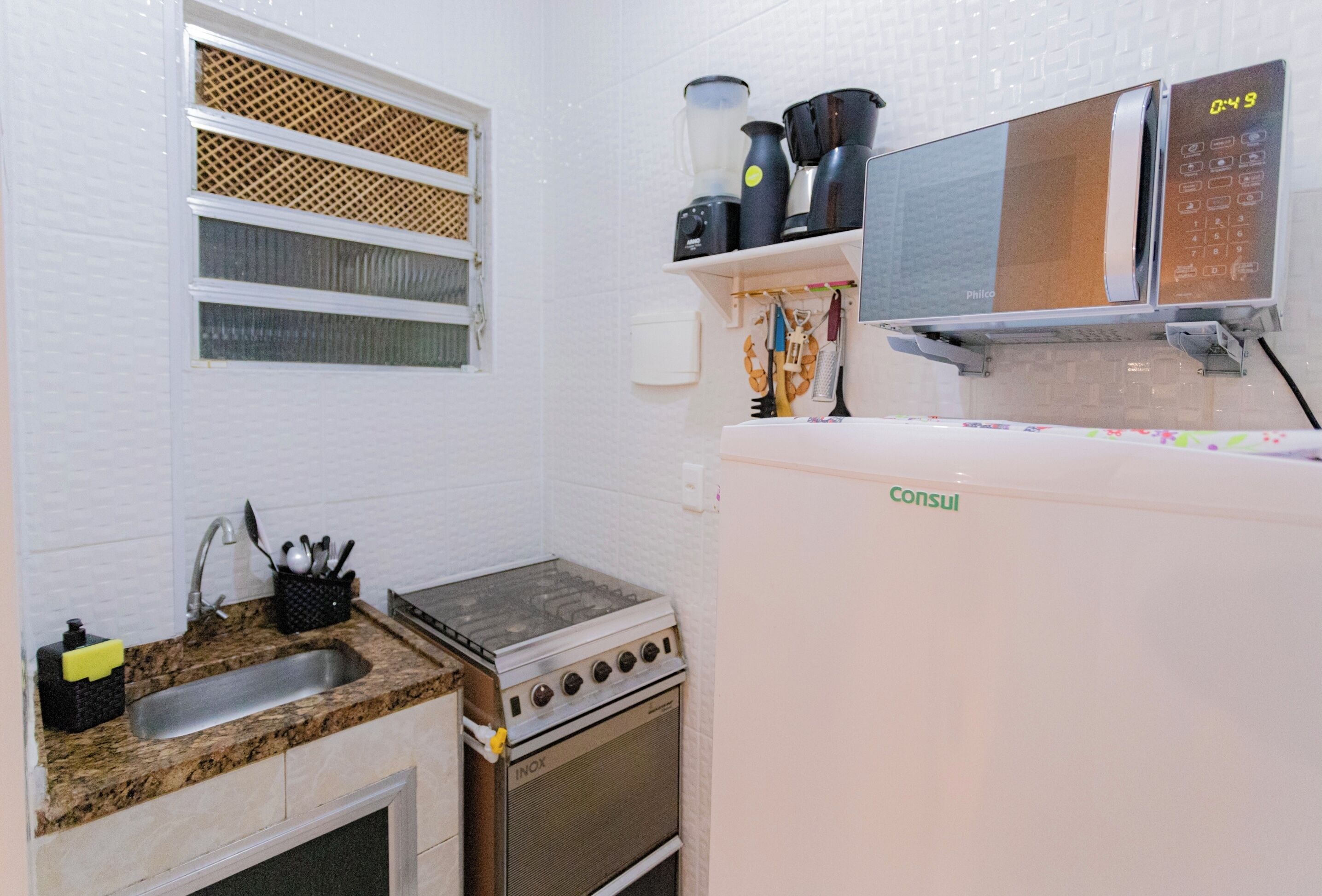 A compact kitchen with a sink, stove, and microwave.