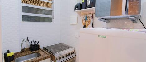 A compact kitchen with a sink, stove, and microwave.