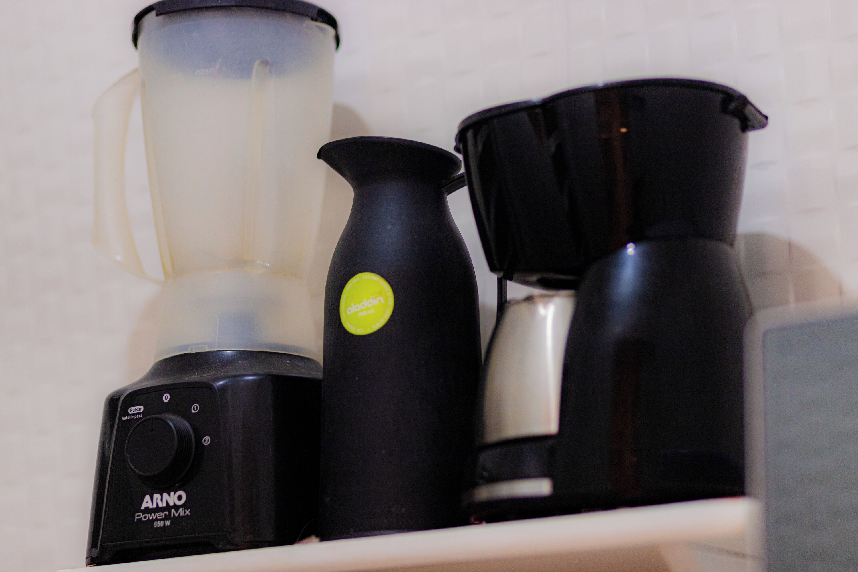 Une cuisine avec un mixeur, un pichet et une machine à café sur un plan de travail.