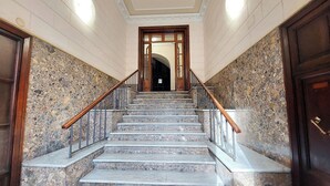 A marble staircase with wooden railings and a wooden door at the top.