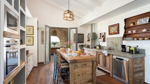 A modern kitchen with a central island, wooden cabinets, and a stone backsplash.