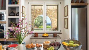 A kitchen with a stone wall, a window with a view, and various food items on the counter.