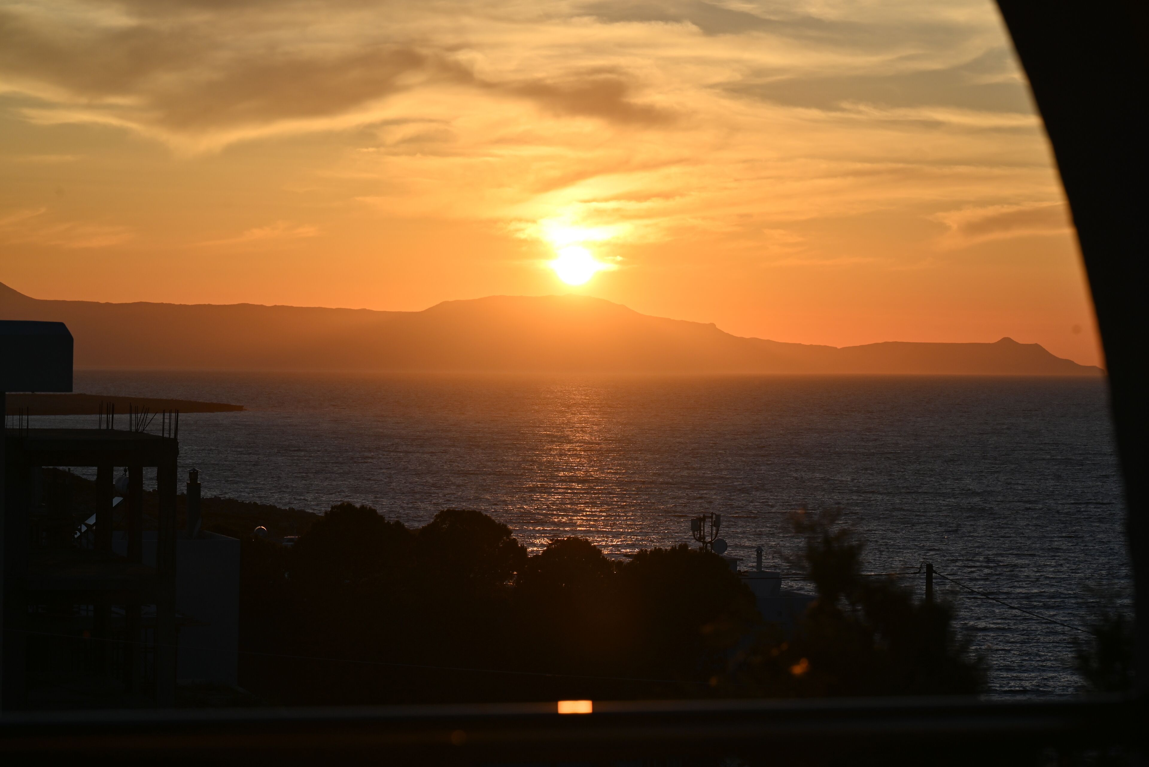 Un coucher de soleil sur l’océan, avec des montagnes en arrière-plan.