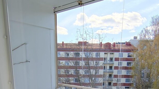 Un balcón con una silla blanca, una mesita redonda pequeña y una jardinera con plantas verdes.