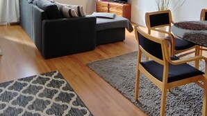 Una sala de estar moderna con sofá, televisor y comedor.