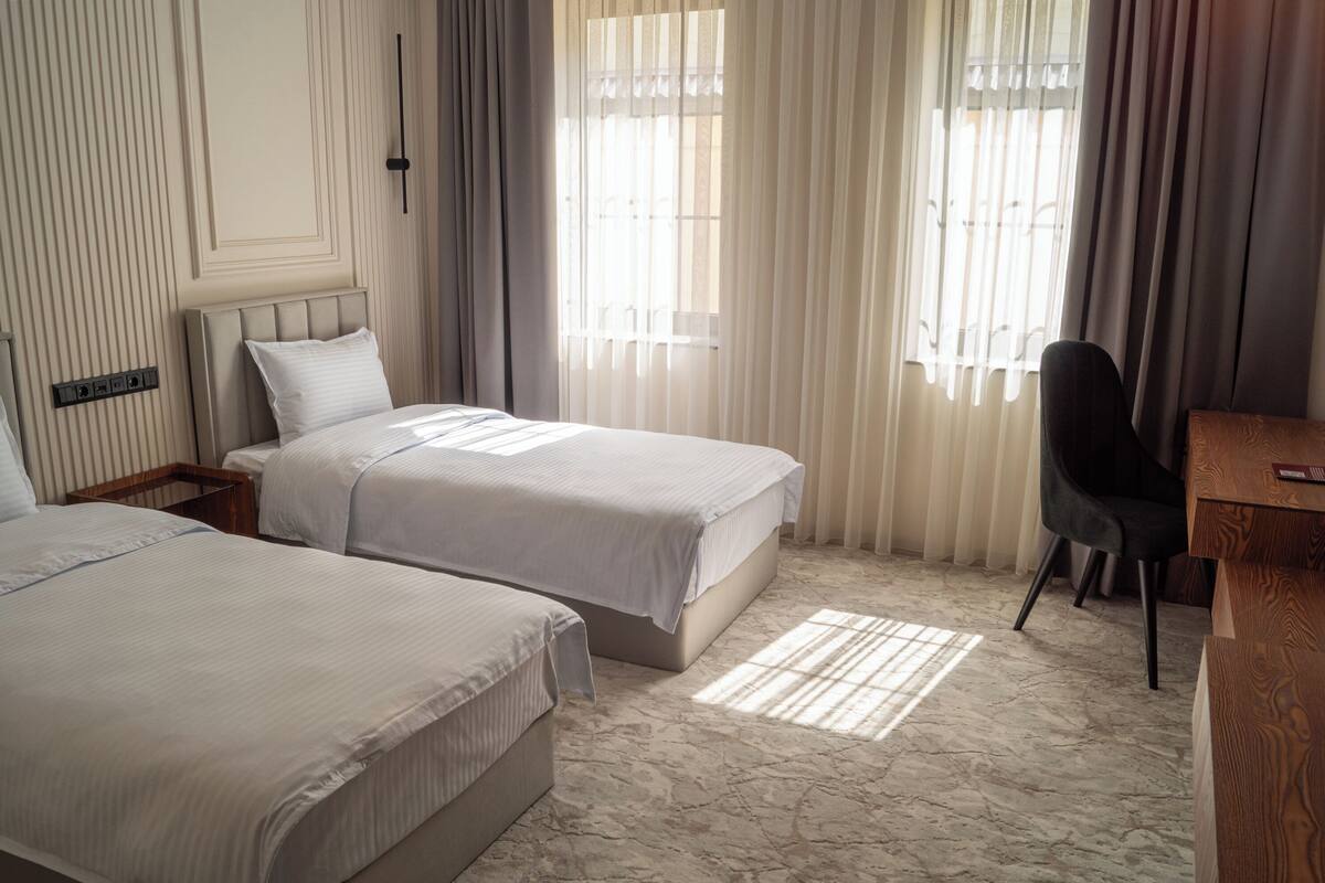 A hotel room with two beds, a desk, and a chair.