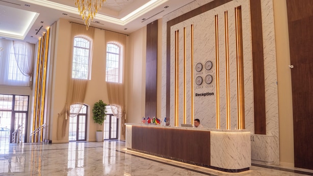 A hotel reception area with a marble reception desk, a chandelier, and a reception sign. - Meridian Plaza by Reikartz (Samarkand)