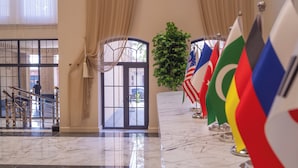 A lobby with a marble floor, a staircase, and flags of various countries. - Meridian Plaza by Reikartz (Samarkand)