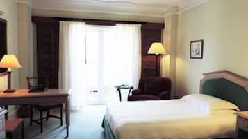 A hotel room with a bed, a desk, a chair, and a lamp.