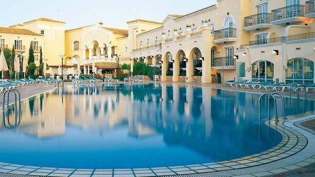 Una piscina rodeada de edificios con balcones y una zona cubierta.
